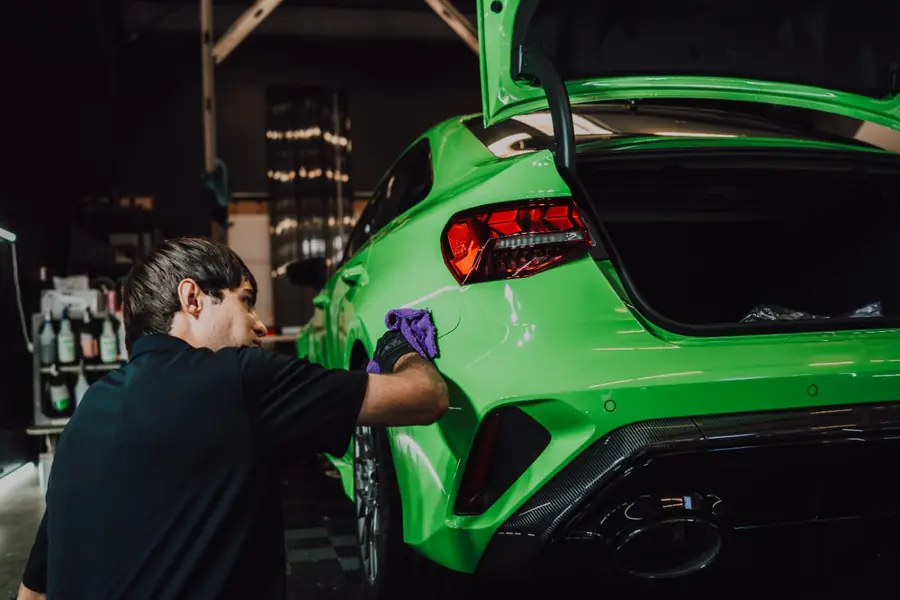 Technician finishing a green Audi RS3 after coating work at Evo Solutions